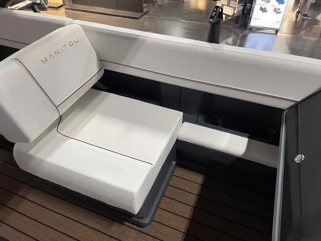 Slide: The Image of 2024 Manitou EXPLORE 24 MAX SGP boat interior with white seating and wood flooring. - 14