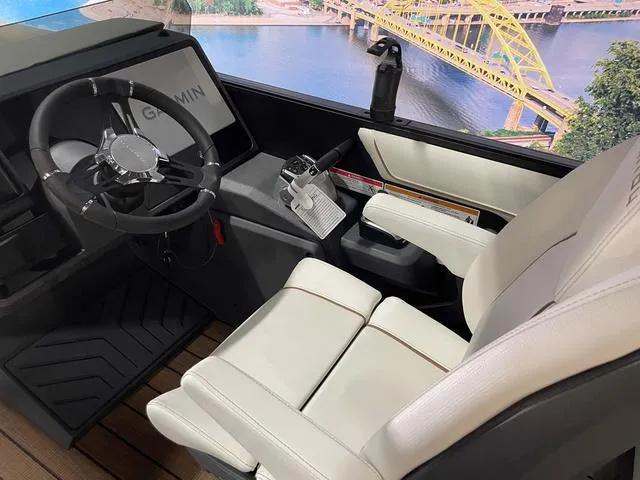 Slide: The Image of 2024 Manitou EXPLORE 24 MAX SGP boat interior with steering wheel and white seating. - 15