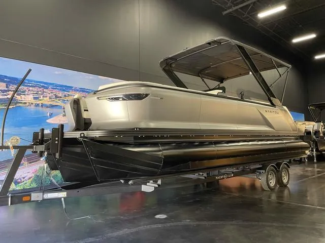 Slide: The Image of 2024 Manitou EXPLORE 24 MAX SGP dual engine boat displayed indoors. - 7