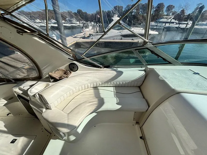 Slide: The Image of 2000 Cruisers Yachts 3375 Express interior with white seating and marina view. - 11