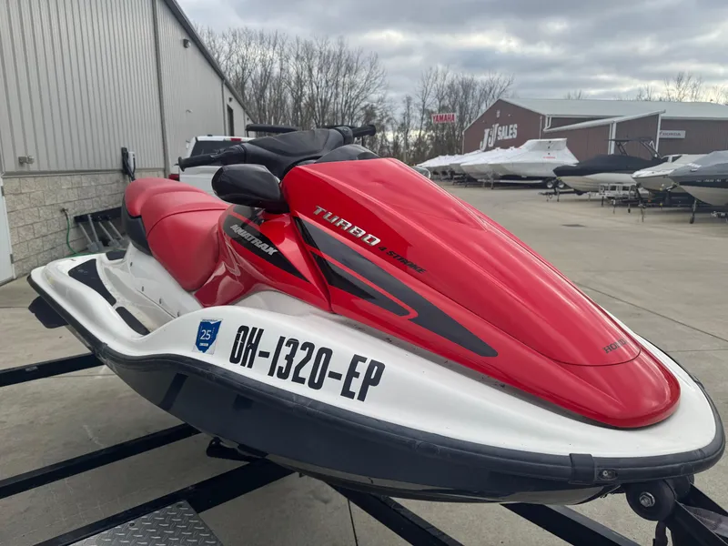 Slide: The Image of 2006 Honda Aquatrax F-12X jet ski, red and white, parked outdoors. - 2