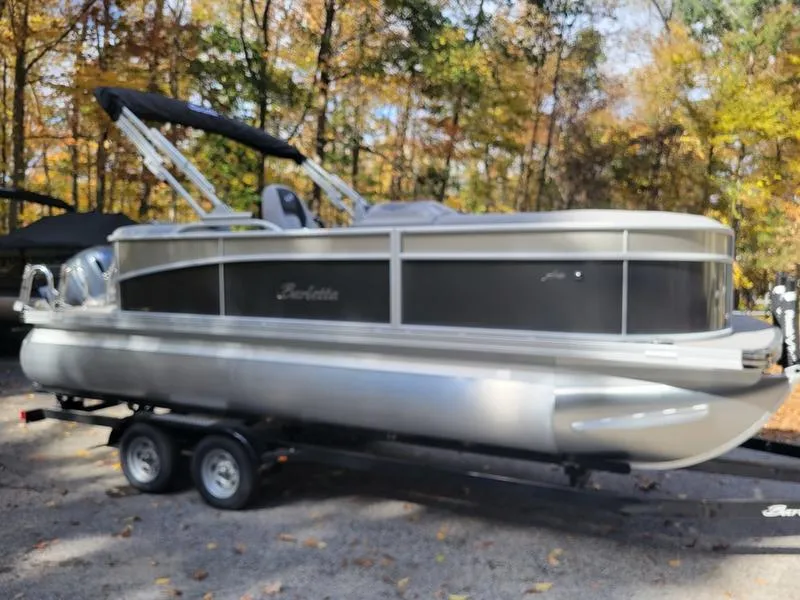 Slide: The Image of 2025 Barletta A20QC pontoon boat on trailer in wooded area. - 1