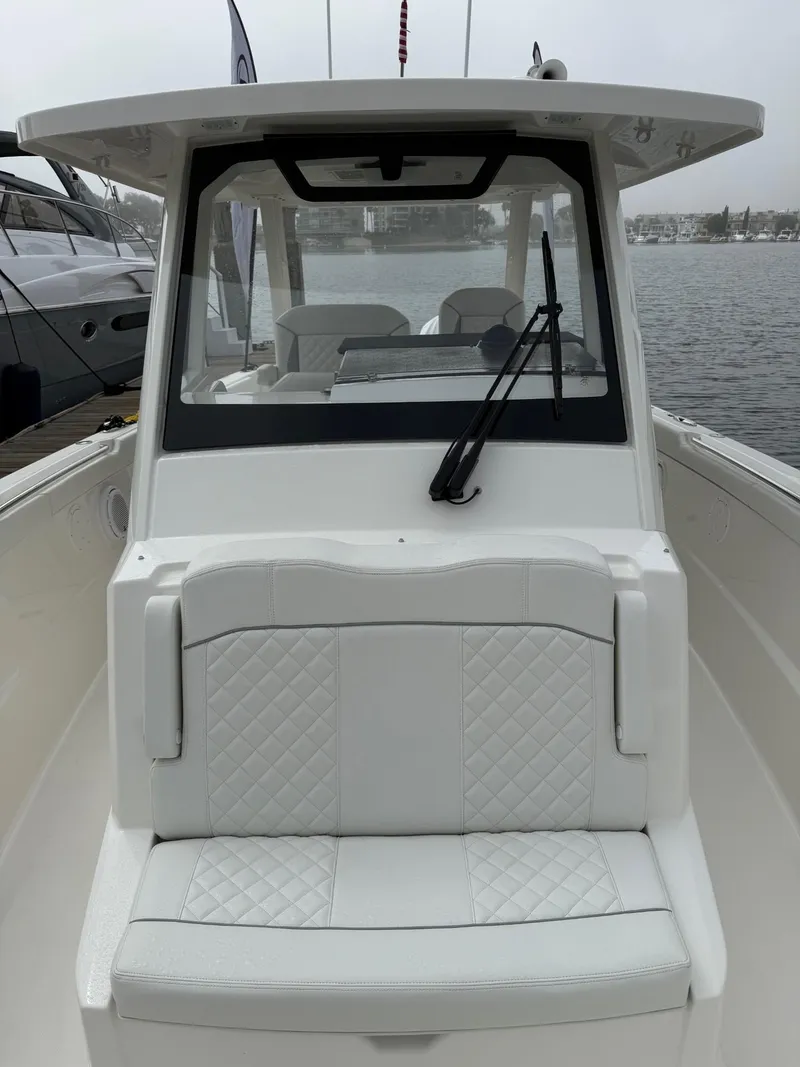 Slide: The Image of 2025 Pursuit S 328 Sport boat with white seating and windshield, docked by the water. - 19