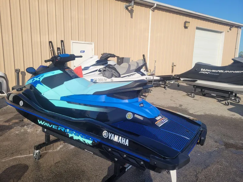 Slide: The Image of 2022 Yamaha WaveRunner EX Deluxe in blue, parked outside a storage facility. - 2