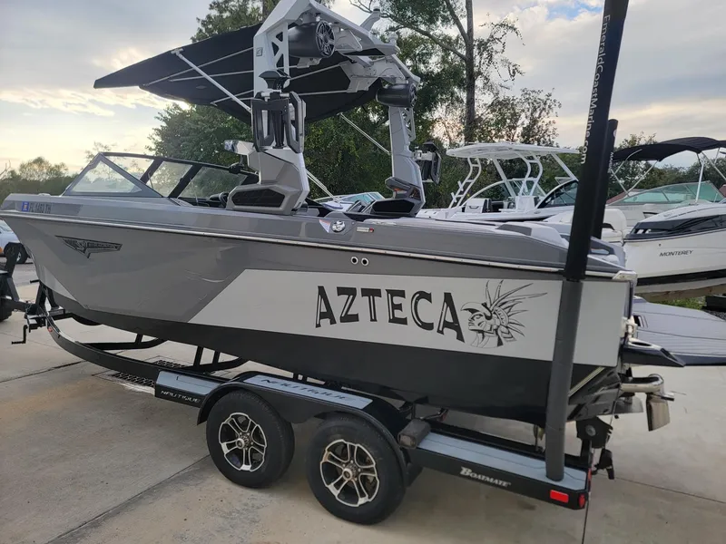 Slide: The Image of 2022 Nautique Super Air Nautique S21 boat on trailer, labeled "Azteca," in a marina setting. - 4