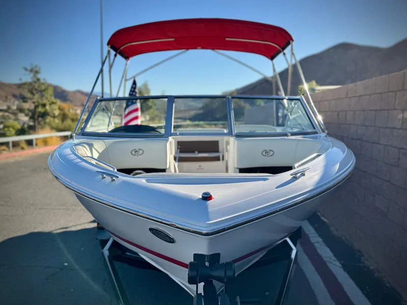 Slide: The Image of 2017 Cobalt 220S boat with red canopy and American flag, parked on a sunny day. - 2