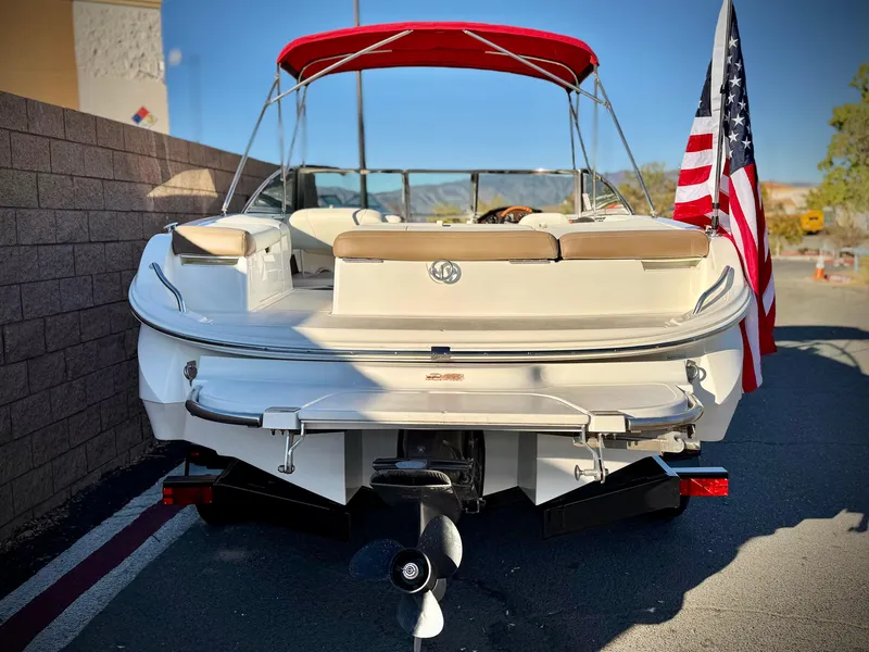 Slide: The Image of 2017 Cobalt 220S boat with red canopy and American flag, parked outdoors. - 5