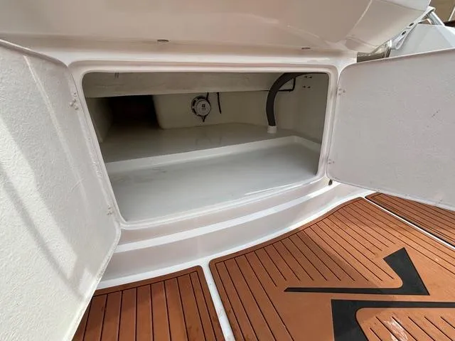 Slide: The Image of Open storage compartment on 2023 NX Boats 360 with teak flooring. - 13