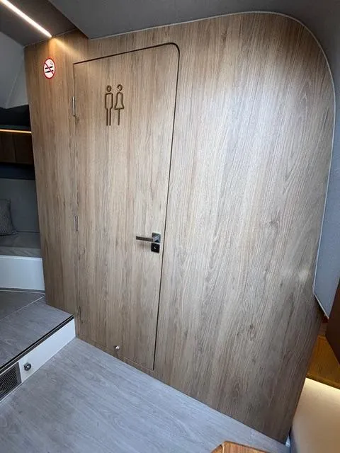 Slide: The Image of Interior of 2023 NX Boats 360, featuring a wooden restroom door. - 35