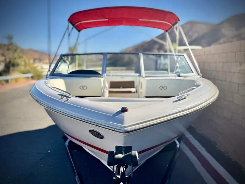 Slide: The Image of 2017 Cobalt 220S boat with red canopy, parked on a trailer, scenic background. - 2