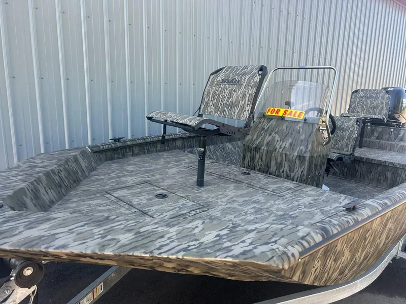 Slide: The Image of 2024 SeaArk Shadow 187 boat for sale, camo design, parked by metal building. - 3