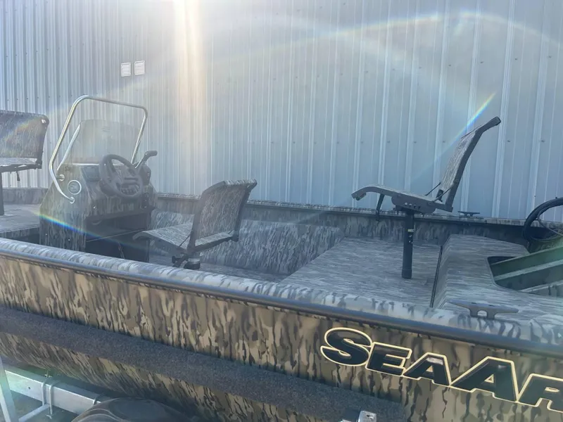 Slide: The Image of 2024 SeaArk Shadow 187 boat with camouflage design, parked near a metal building. - 5