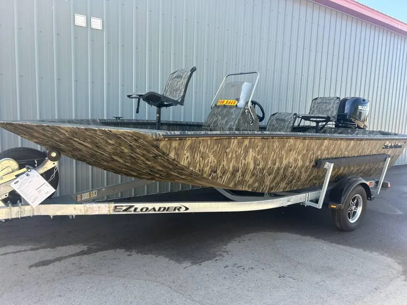 Slide: The Image of 2024 SeaArk Shadow 187 boat on EZ Loader trailer, camo design, parked by metal building. - 9