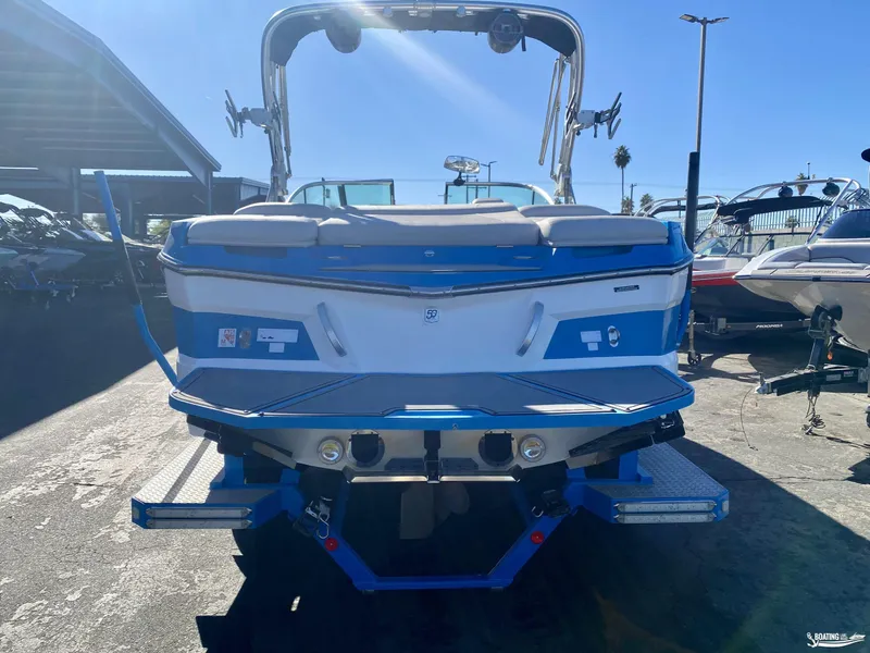 Slide: The Image of 2018 MasterCraft XT22 boat, blue and white, rear view in a marina setting. - 3