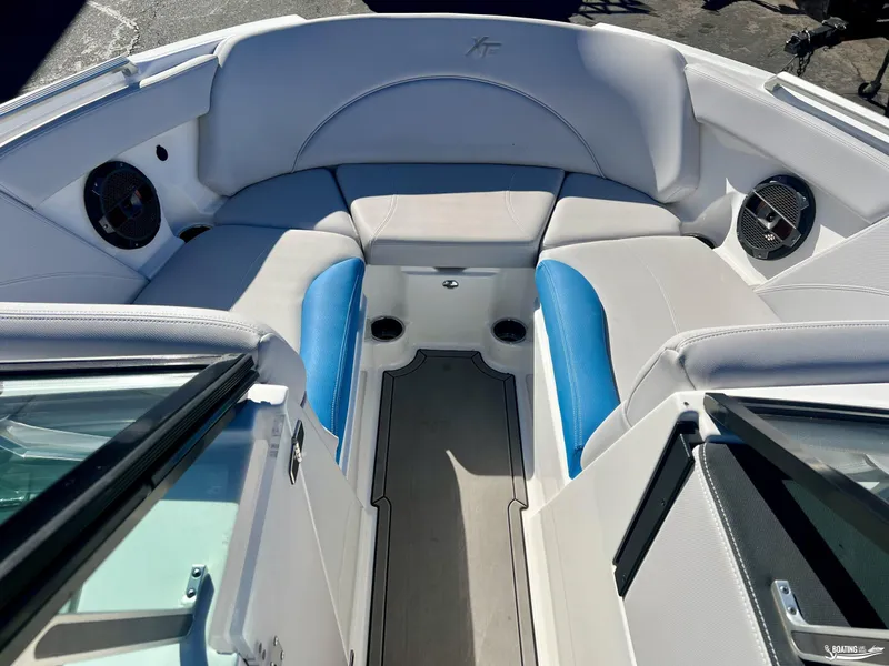 Slide: The Image of 2018 MasterCraft XT22 boat interior with white and blue seating, cup holders, and speakers. - 6