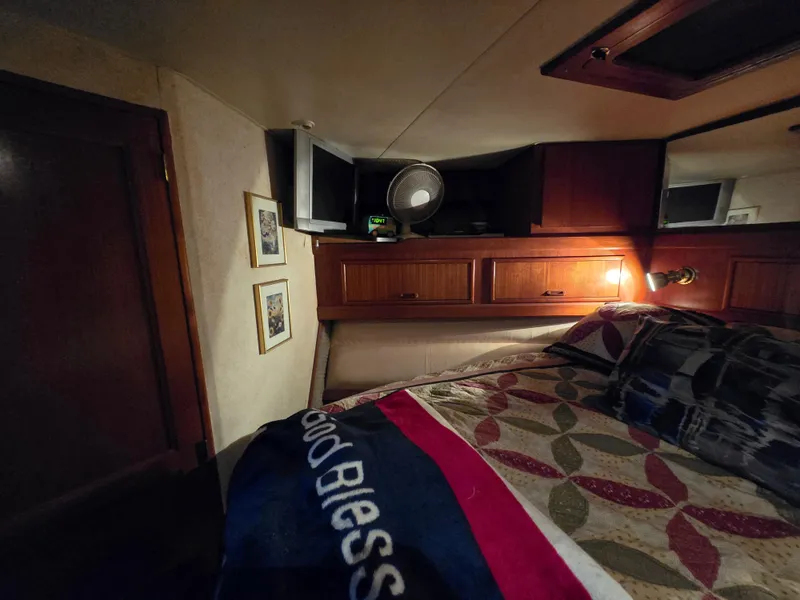 Slide: The Image of Cozy bedroom interior of 1995 Egg Harbor 42 Convertible yacht with quilted bedding and wooden cabinets. - 30