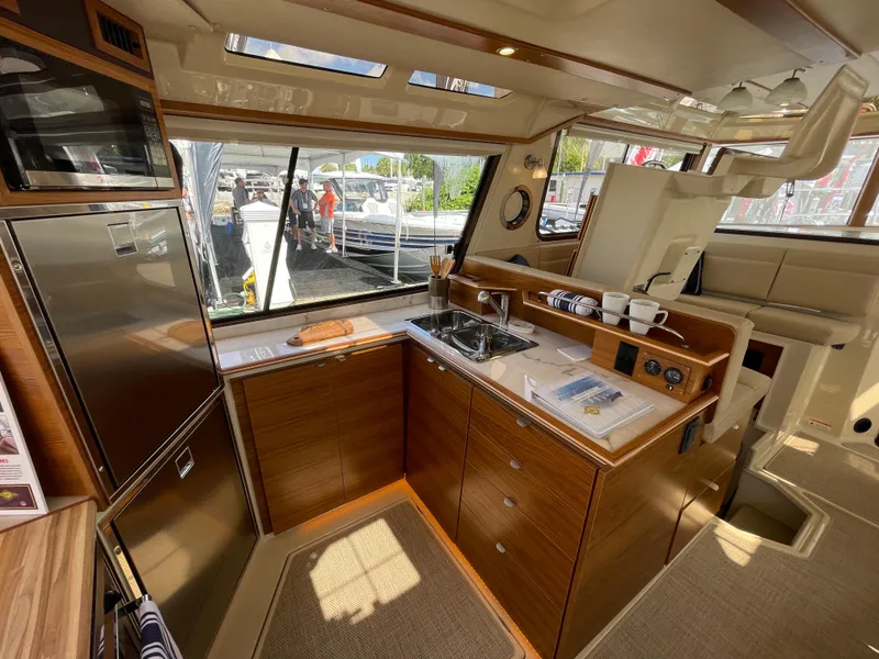 Slide: The Image of Interior of 2025 Ranger Tugs 43 Command Bridge, featuring a modern kitchen with wood cabinetry. - 14