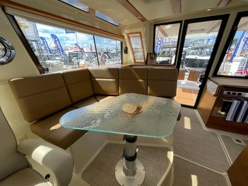 Slide: The Image of 2025 Ranger Tugs 43 Command Bridge interior with glass table and plush seating. - 17