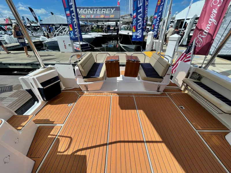 Slide: The Image of 2025 Ranger Tugs 43 Command Bridge deck at a boat show, featuring seating and wood flooring. - 9