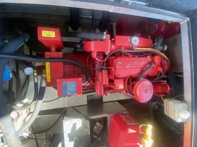 Slide: The Image of Engine compartment of a 2000 Sumerset 18x85 houseboat, featuring red machinery and components. - 27