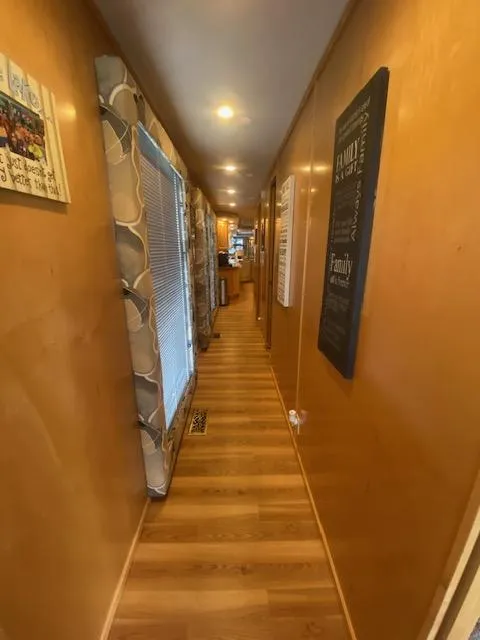 Slide: The Image of Narrow hallway inside 2000 Sumerset 18x85 houseboat with wooden flooring and wall decor. - 8