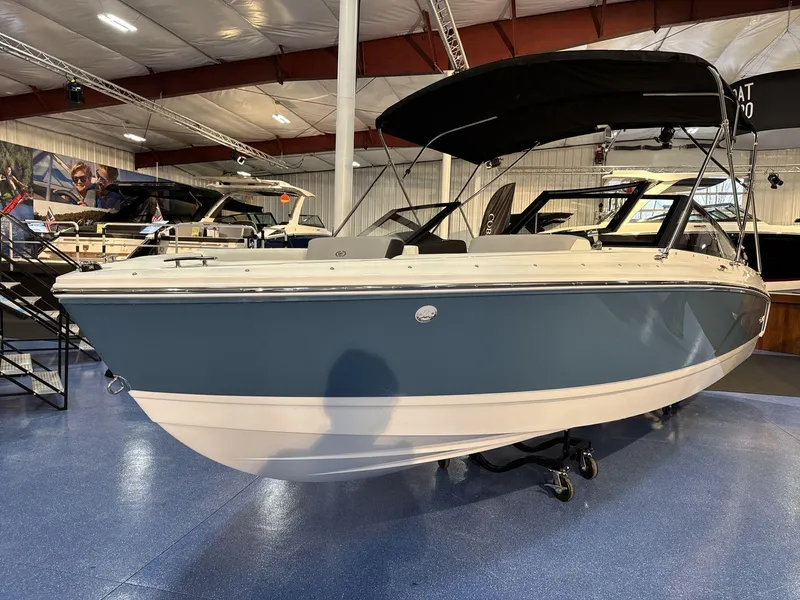 Slide: The Image of 2025 Cobalt CS22 boat displayed in a showroom with blue and white exterior. - 2