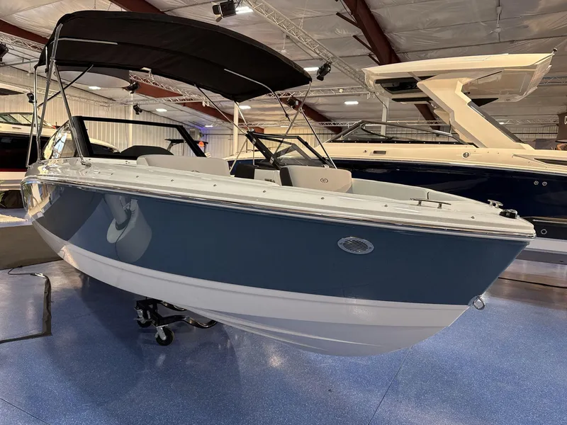 Slide: The Image of 2025 Cobalt CS22 boat displayed indoors with sleek design and black canopy. - 3