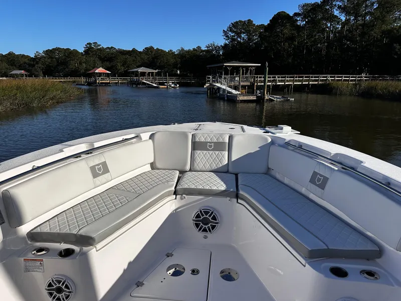 Slide: The Image of 2025 Sea Fox 328 Commander boat interior with cushioned seating, docked in a serene waterway. - 21