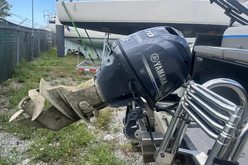 Slide: The Image of Outboard motor on 2023 Qwest Lanai 818 boat, parked near other vessels. - 11
