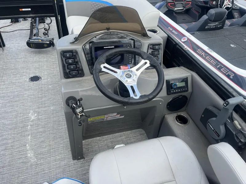 Slide: The Image of 2023 Qwest Lanai 818 boat dashboard with steering wheel and control panel. - 9