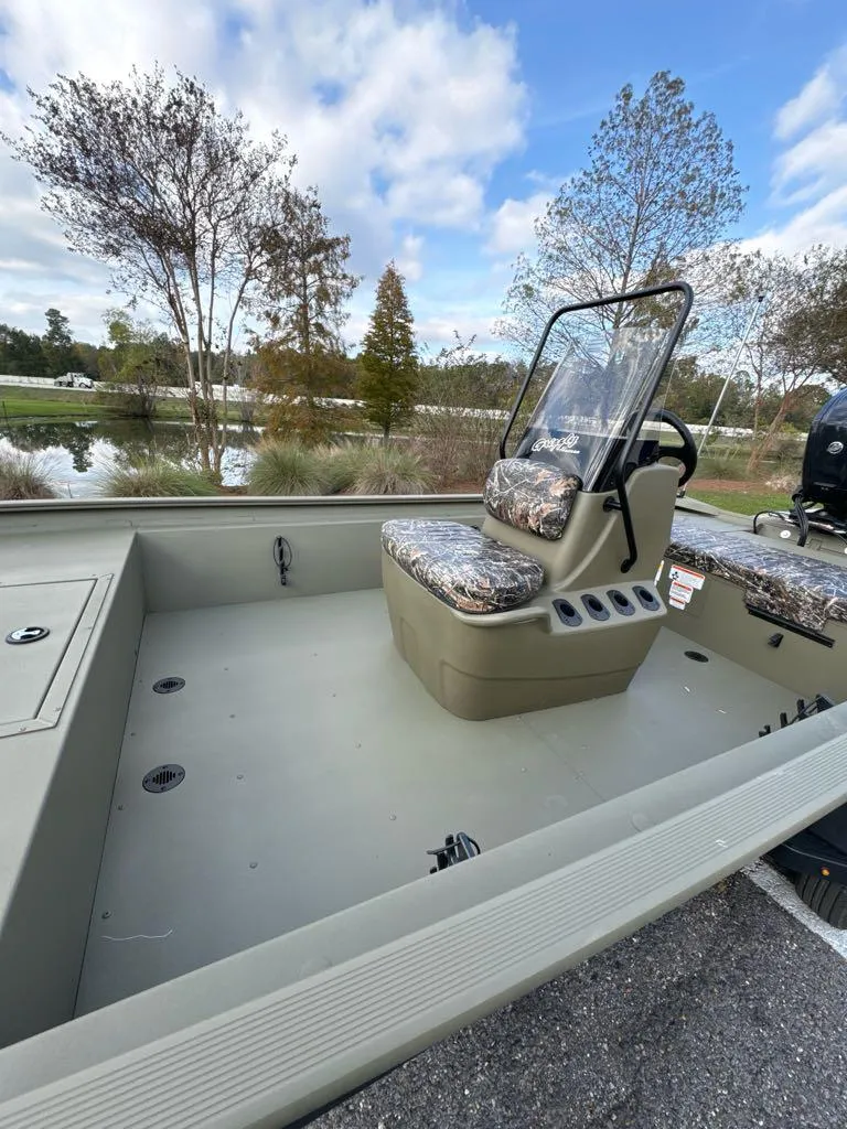 Slide: The Image of 2025 Tracker Grizzly 1860 CC boat with camo seats, parked near a lake. - 5