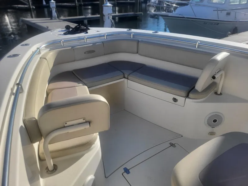 Slide: The Image of 2016 Cobia 277 Center Console boat interior with cushioned seating at a marina. - 19