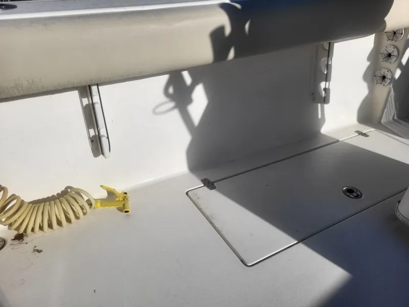 Slide: The Image of 2016 Cobia 277 Center Console deck with storage compartment and coiled hose. - 23