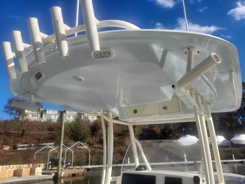 Slide: The Image of 2016 Cobia 277 Center Console boat with rod holders and T-top, docked under a clear sky. - 38