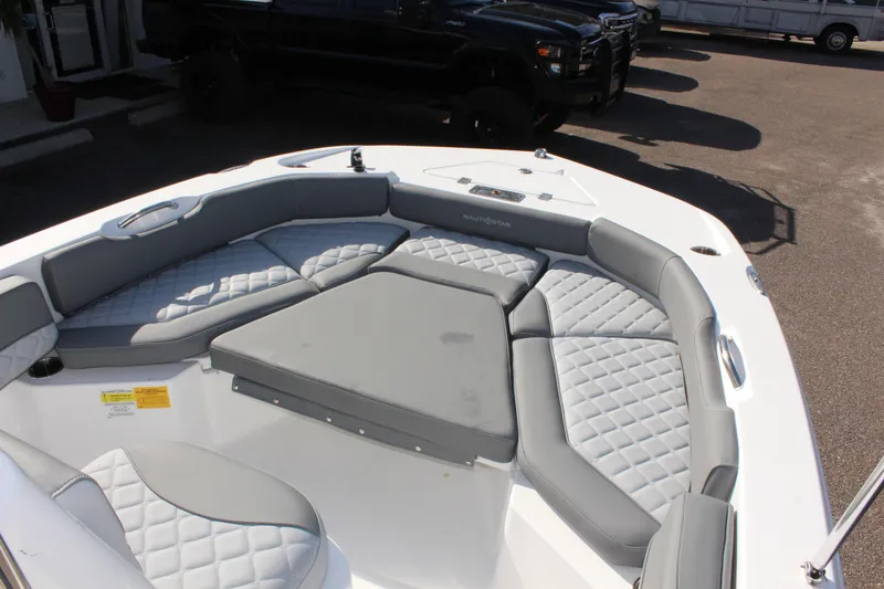 Slide: The Image of 2025 NauticStar 191 Hybrid boat with gray cushioned seating in a sunny outdoor setting. - 18
