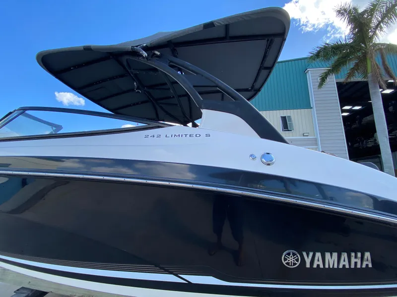 Slide: The Image of 2018 Yamaha Boats 242 Limited S with sleek design and canopy, docked near palm trees. - 4