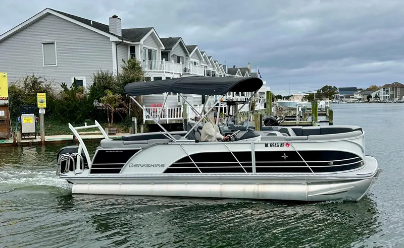Slide: The Image of 2024 Berkshire 23RFX STS 3.0 pontoon boat cruising near waterfront homes. - 24