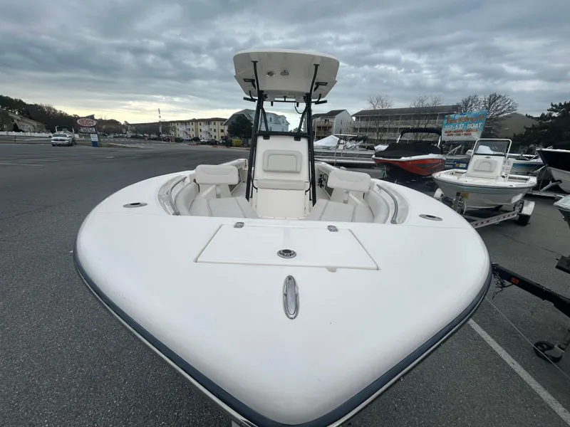 Slide: The Image of 2024 Sea Born LX24 LE boat with spacious seating, parked outdoors under cloudy skies. - 14