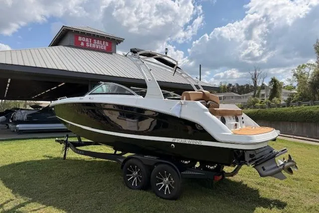 The Image of 2025 Four Winns HD3 boat on trailer at dealership under blue sky. - 0