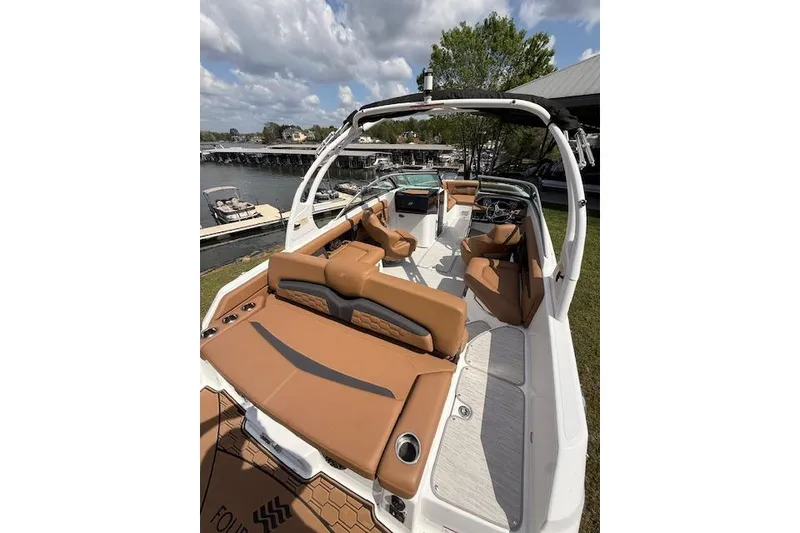 Slide: The Image of 2025 Four Winns HD3 boat with tan seating, docked by a scenic lake. - 15