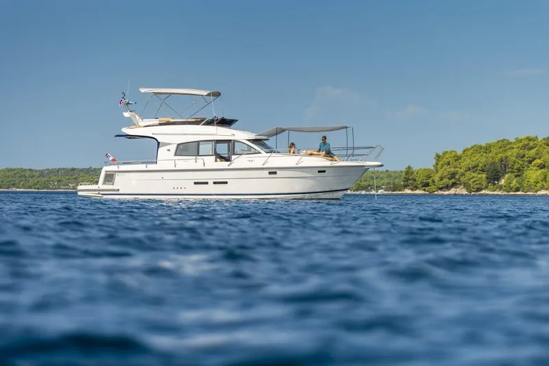 Slide: The Image of 2025 Nimbus 405 Flybridge yacht cruising on a sunny day. - 2