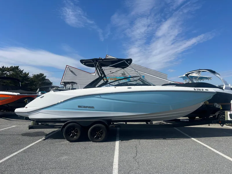 Slide: The Image of 2024 Scarab 255 ID boat on trailer, parked outdoors under a clear blue sky. - 0