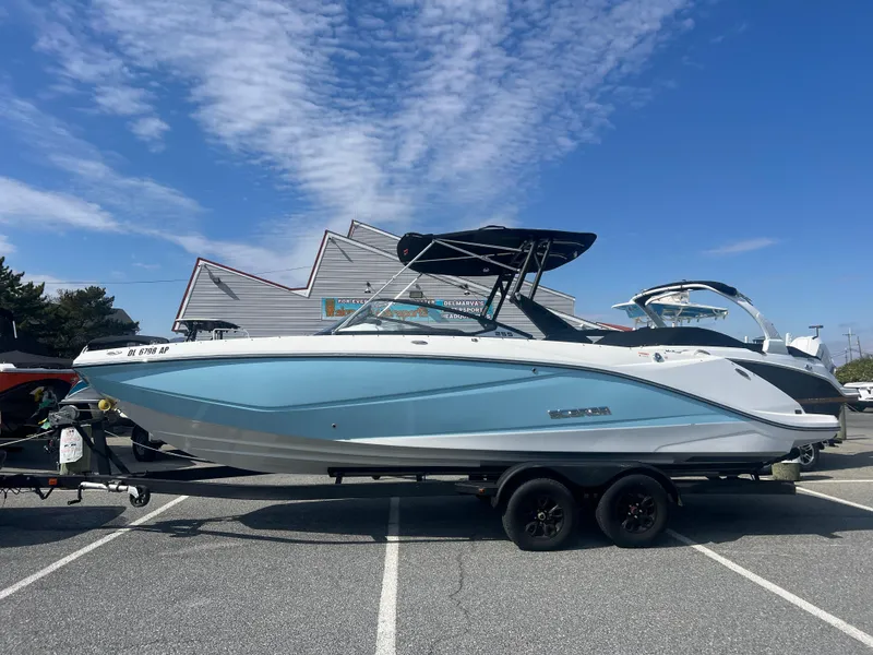 Slide: The Image of 2024 Scarab 255 ID boat on trailer, blue and white, parked outdoors under clear sky. - 1