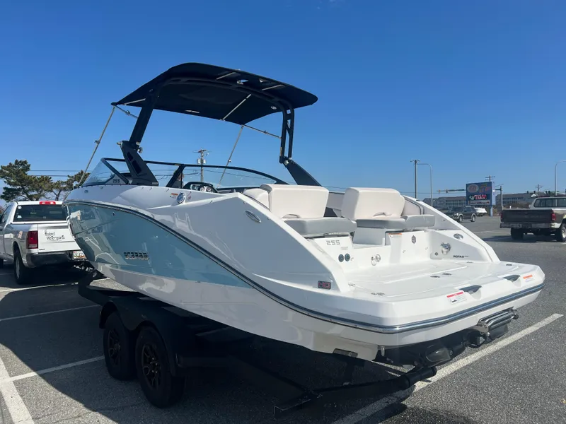 Slide: The Image of 2024 Scarab 255 ID boat on trailer, parked in a lot under clear blue sky. - 3