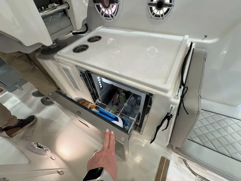 Slide: The Image of 2025 Pursuit OS 325 Offshore boat interior with open mini fridge and speakers. - 15