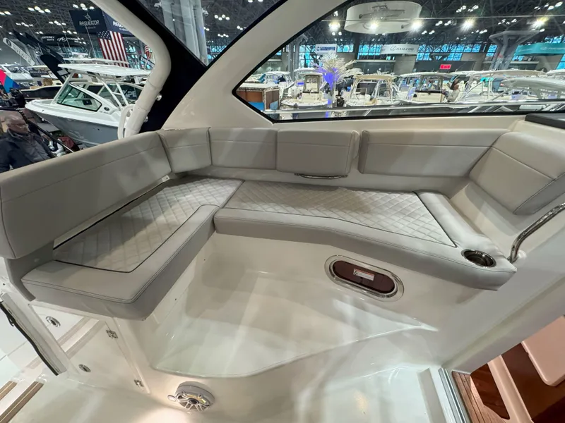 Slide: The Image of 2025 Pursuit OS 325 Offshore boat interior with cushioned seating at a boat show. - 16