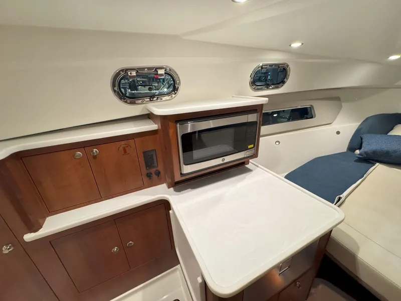 Slide: The Image of 2025 Pursuit OS 325 Offshore cabin interior with microwave and wooden cabinetry. - 22