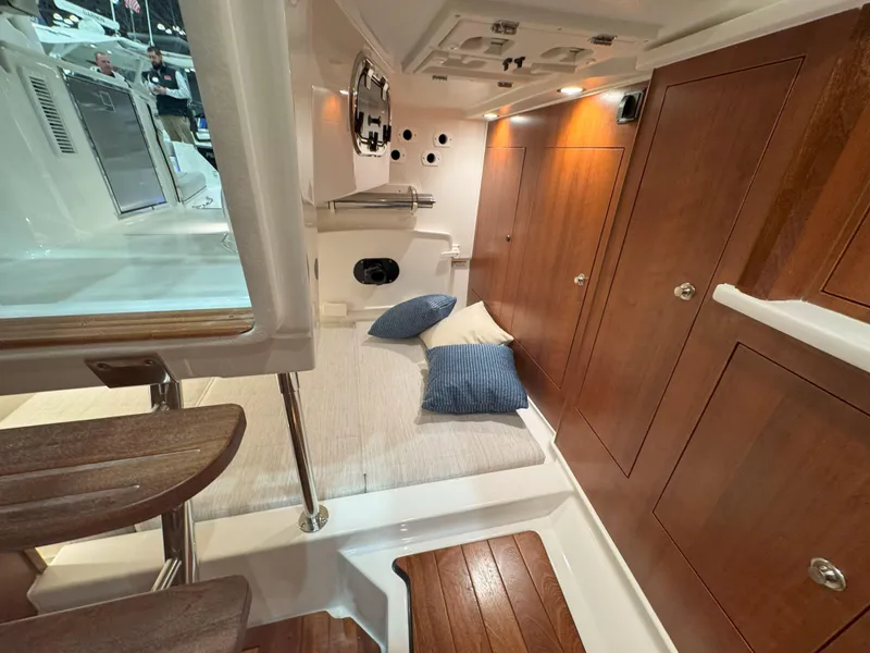 Slide: The Image of 2025 Pursuit OS 325 Offshore cabin interior with wooden finishes and cozy bedding. - 25