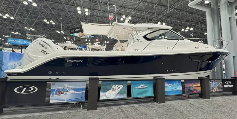 The Image of 2025 Pursuit OS 405 Offshore boat cruising on a serene lake with lush greenery. - 0