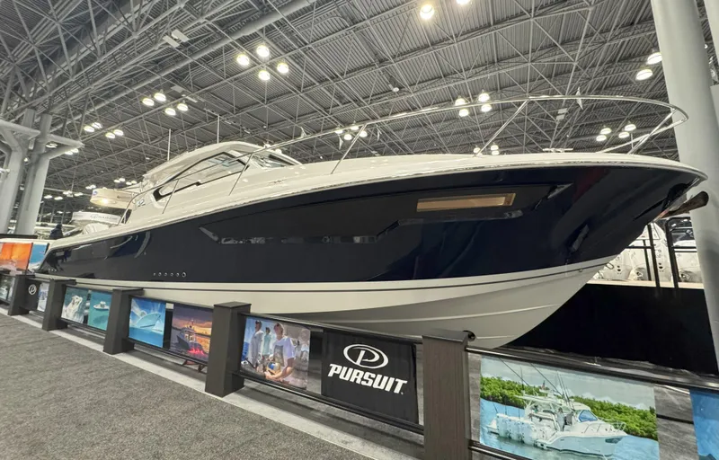 Slide: The Image of 2025 Pursuit OS 405 Offshore boat cruising on a serene lake under a clear blue sky. - 2